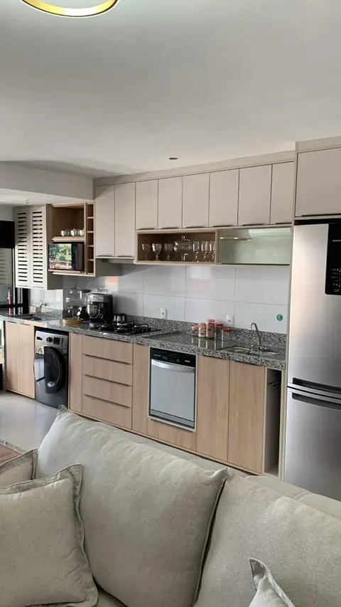 Cozinha planejada integrada à sala, com armários claros e frentes amadeiradas