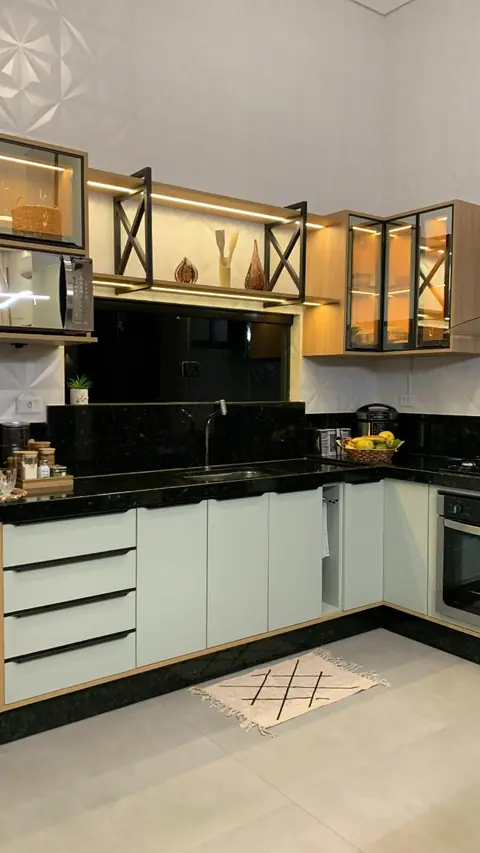 Cozinha em L com armários brancos, aéreos com vidro e prateleiras iluminadas