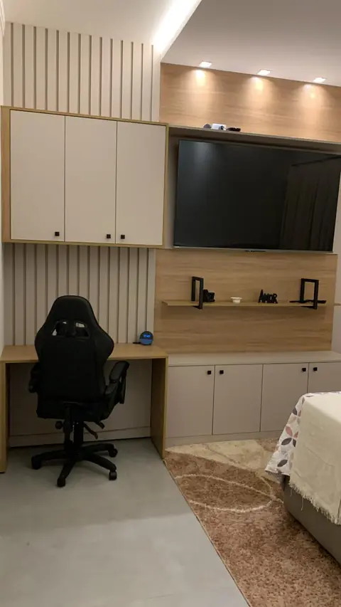 Home office planejado no quarto, com bancada, armários e painel de TV
